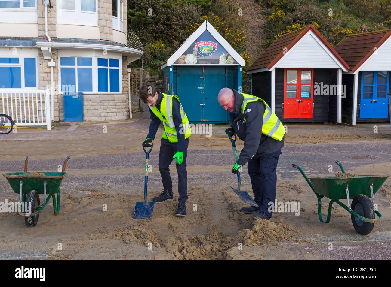 Bournemouth, Dorset, UK. 26th Feb 2020. Councillor Lewis Allison (left), gets stuck in and gives the seafront rangers (Terry, right) a hand to clear the sand from the promenade, blown up from the recent strong winds and Storm Dennis.   Councillor Allison is Labour Councillor for Boscombe West and Portfolio Holder, Cabinet Member, for Tourism, Leisure and Communities at BCP (Bournemouth, Christchurch and Poole) Council.  Credit: Carolyn Jenkins/Alamy Live News Stock Photo