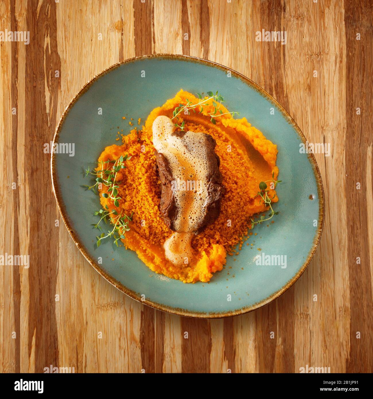 moroccan food, cous cous dish on a plate with sauce, decorated with salad on a wooden table and copy space for text Stock Photo