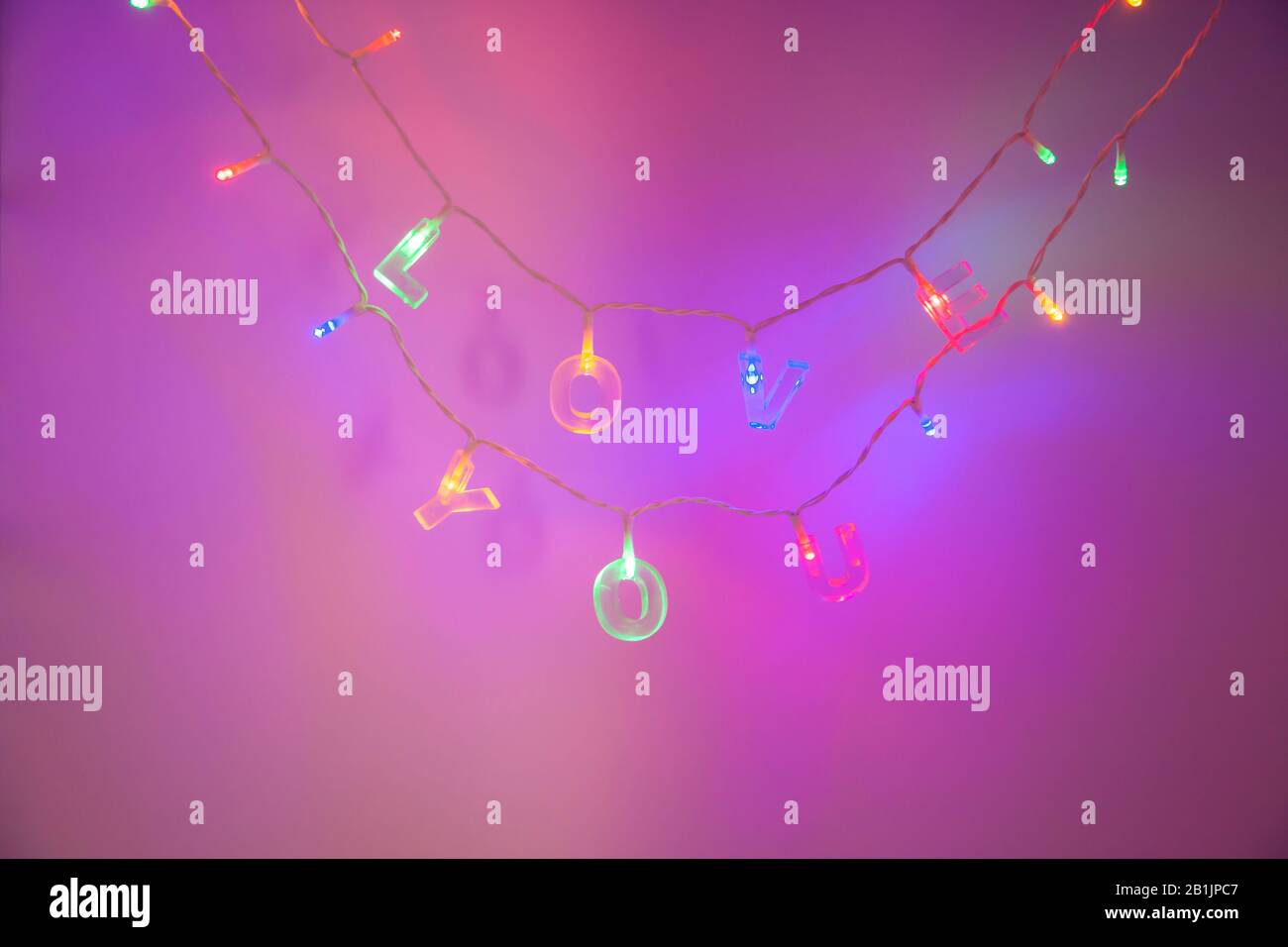 love you letters on a string of lights with purple neon light background Stock Photo