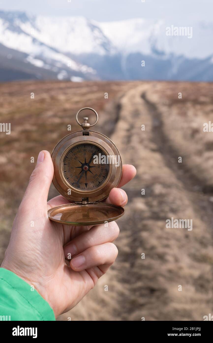 Retro compass in man hand in high mountains. Travel concept. Landscape photography Stock Photo