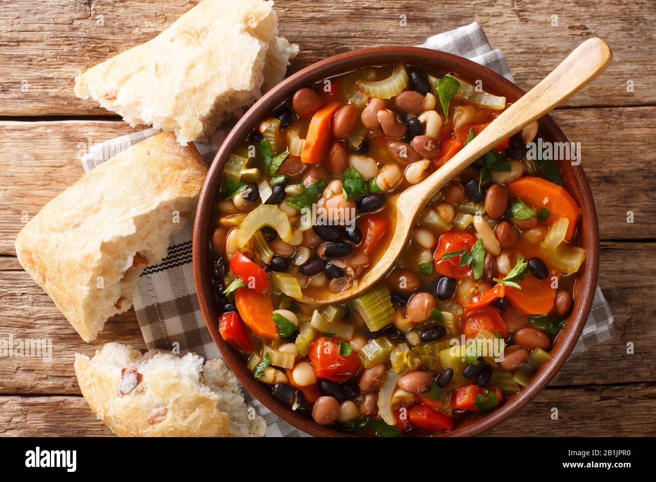 Tasty three bean soup with vegetables in a bowl close-up on the table. Horizontal top view from above Stock Photo