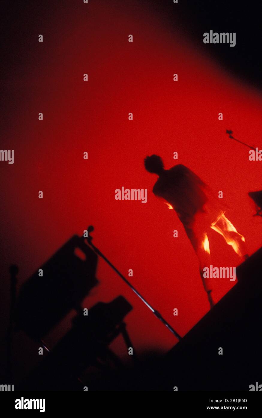 Performer singing on stage. Silhouette from back, red light Stock Photo