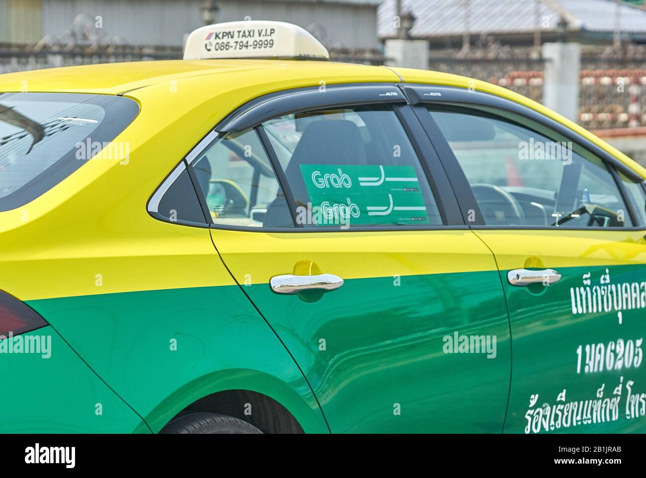 A Bangkok Grab taxi service car, in traditional green and yellow 