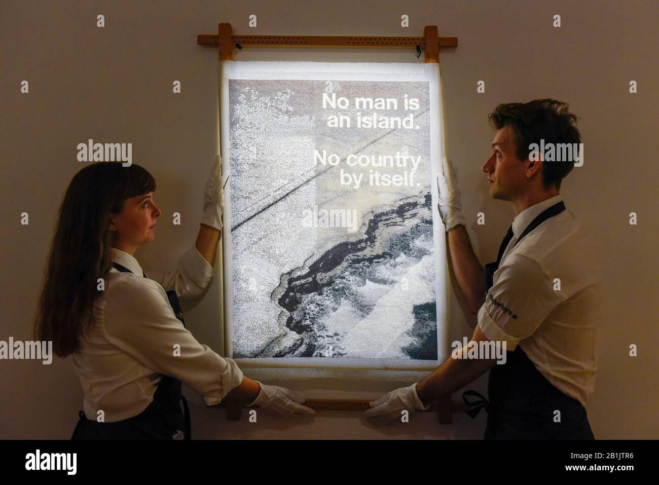 London, UK.  26 February 2020. Technicians present 'No Man Is An Island', 2019, by Wolfgang Tillmans (Starting price GBP10,000). Preview of 'Human Touch', an exhibition of one-of-a-kind artworks by international contemporary artists in collaborations with stitchers in British prisons.  In association with the charity Fine Cell Work, the artworks are on show at Sotheby's New Bond Street 26 February to 3 March 2020.  Credit: Stephen Chung / Alamy Live News Stock Photo