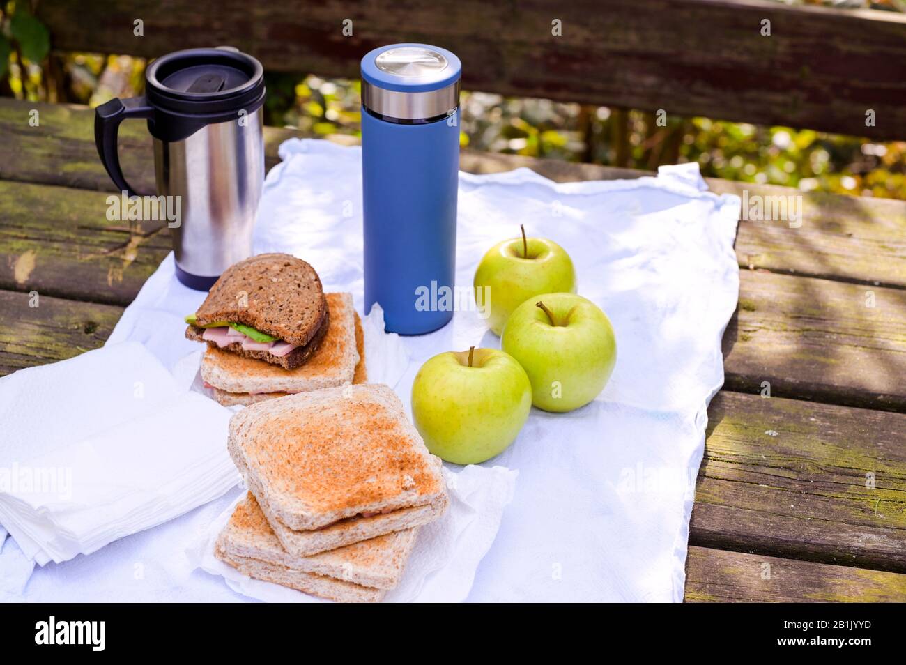 Lunch in the park on an old wooden table. Sandwiches, apples and coffee
