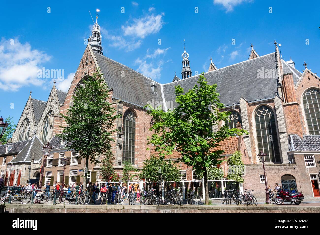 Amsterdam, The Netherlands – June 22, 2016. Exterior view of Oude Kirk church in Amsterdam, with people and bicycles. Oude Kirk is the oldest building Stock Photo