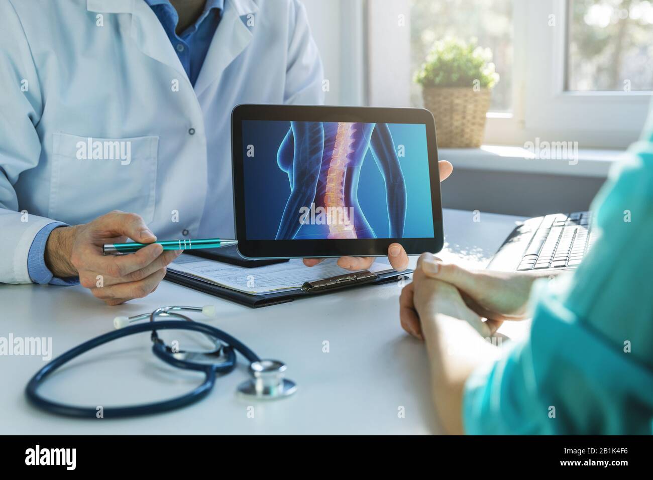 doctor and patient talking about back pain treatment in clinic office Stock Photo