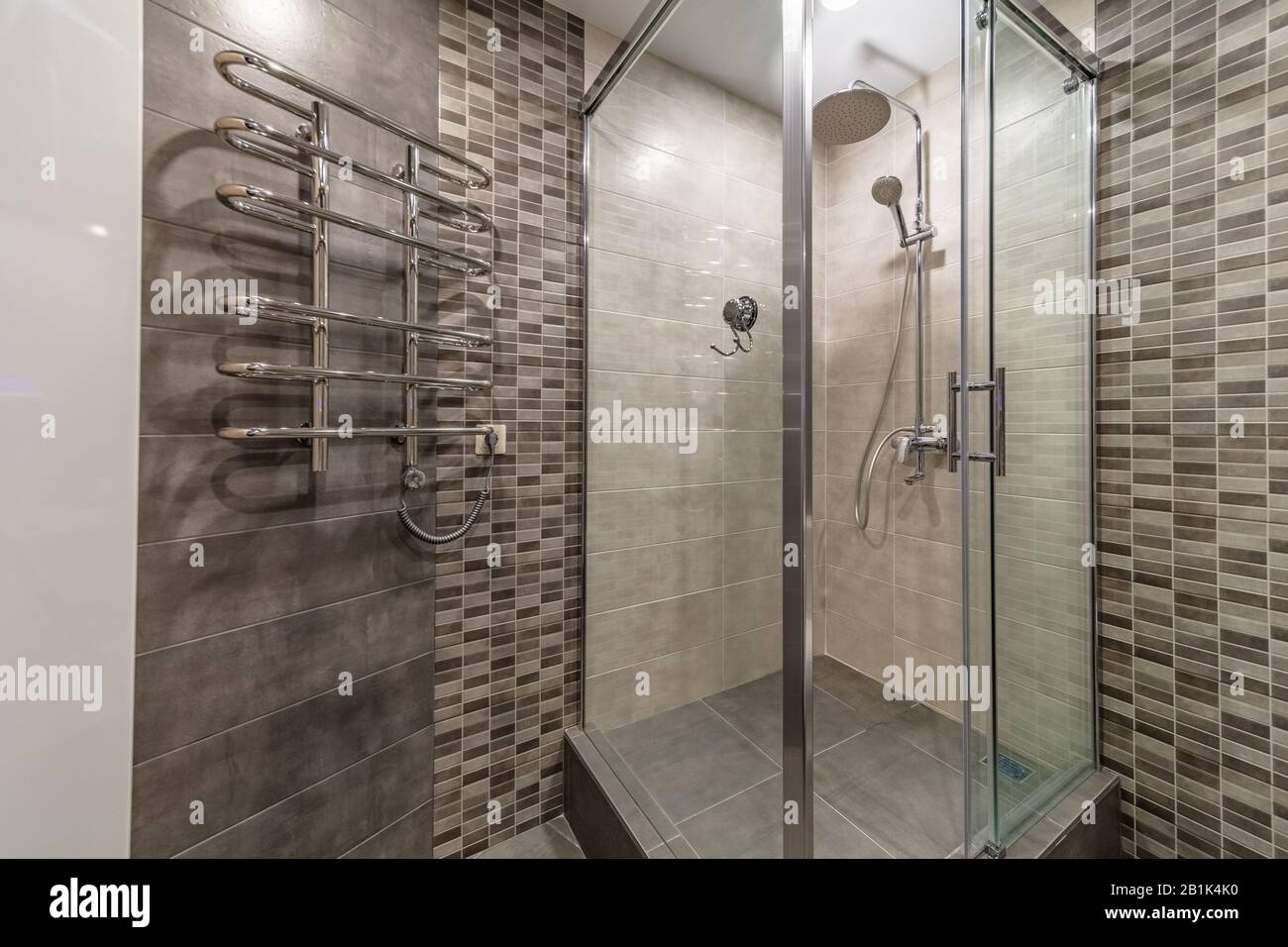 Modern glass shower cabin design in grey brown tiles bathroom interior