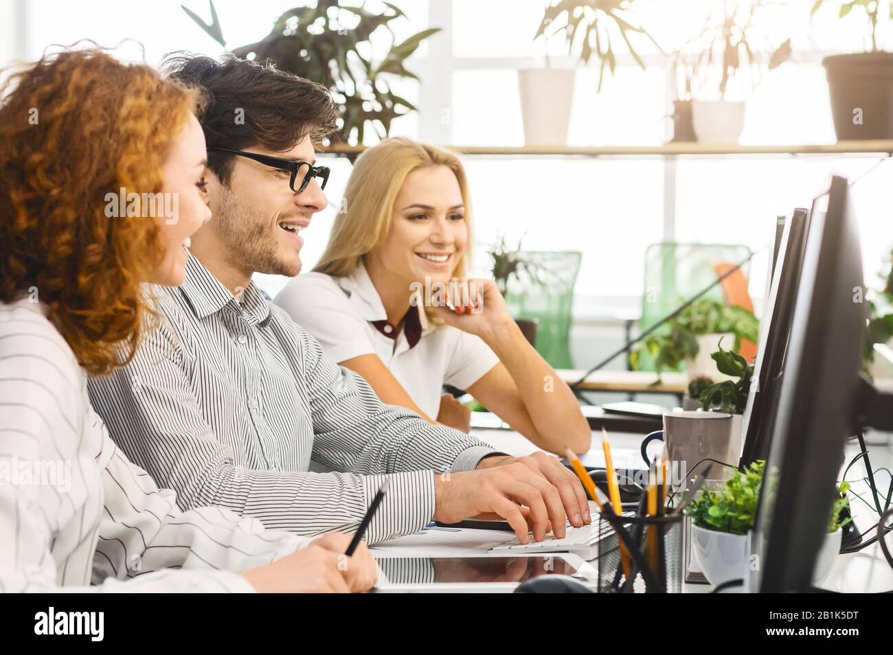 Positive millennial creative team discussing work issues Stock Photo