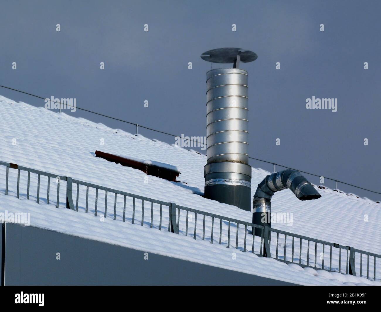 aluminum roof vents under blue sky on snowy sloped roof. galvanized