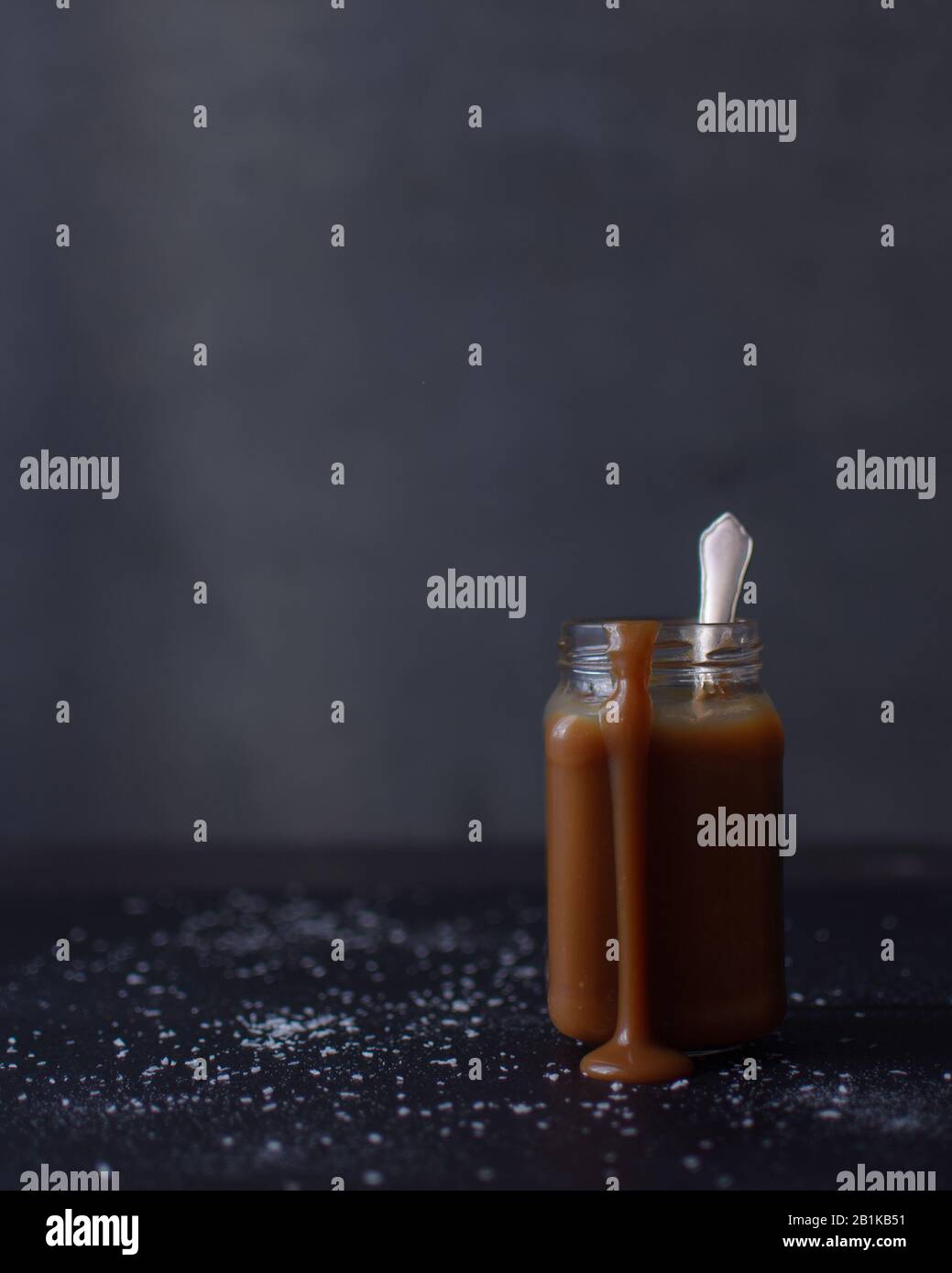 Caramel sauce dripping down the side of a glass jar, Glass jars of salted caramel sauce Stock