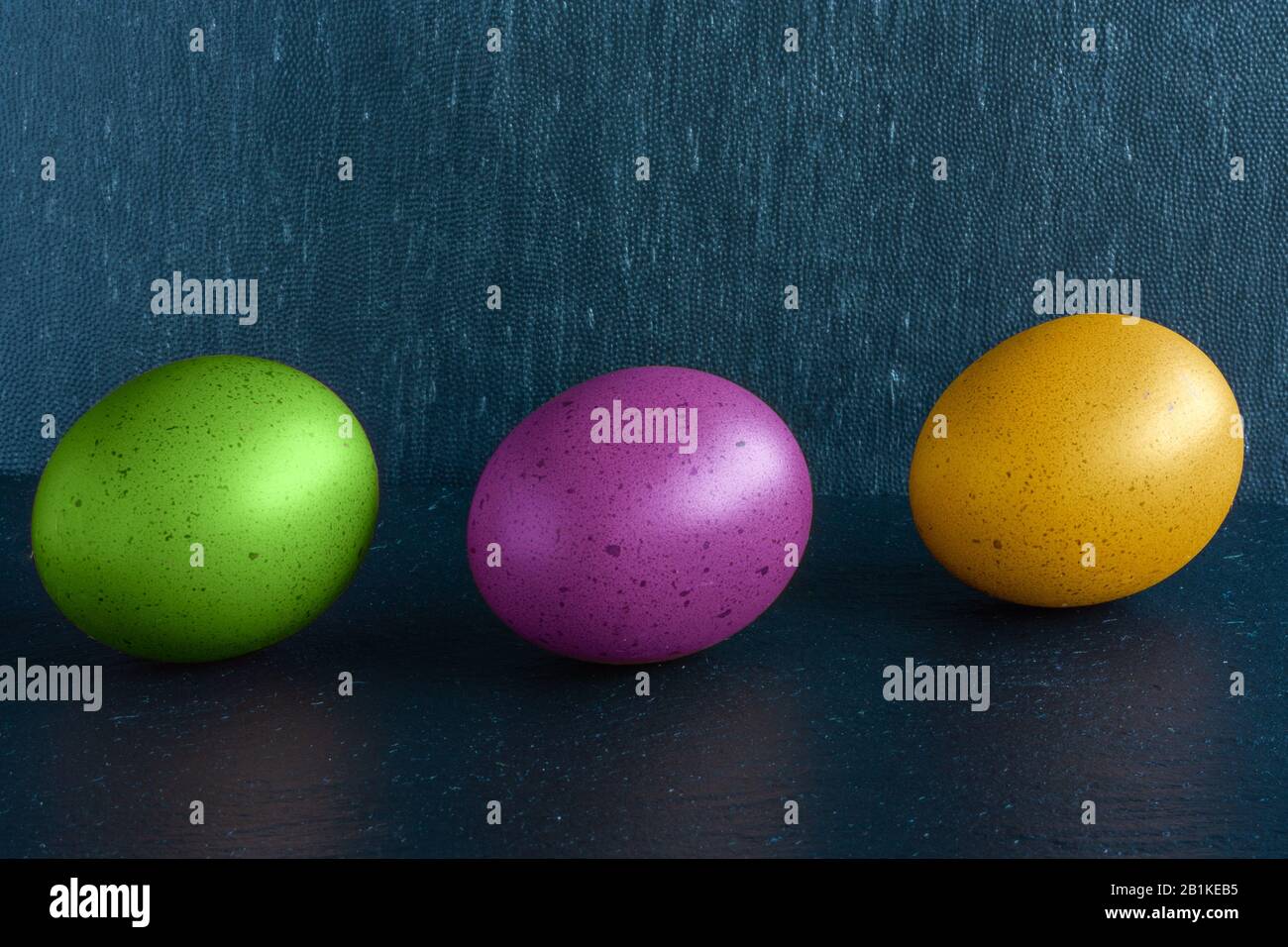 Tree multicolor ester eggs on dack blue background Stock Photo
