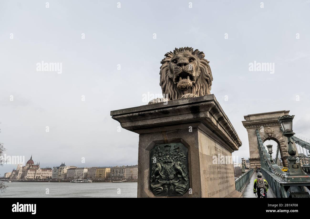 stone Lion statue on the Chain Bridge in Budapest with Hungarian Parliament Building in the Background Stock Photo