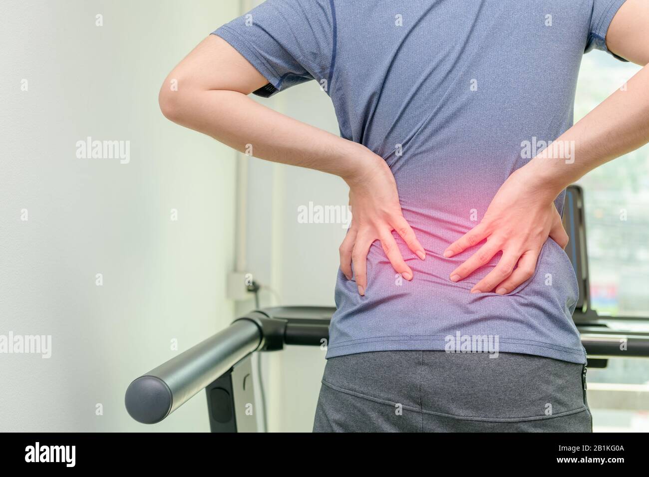 Back pain, close up young man has muscle injury during run on treadmill