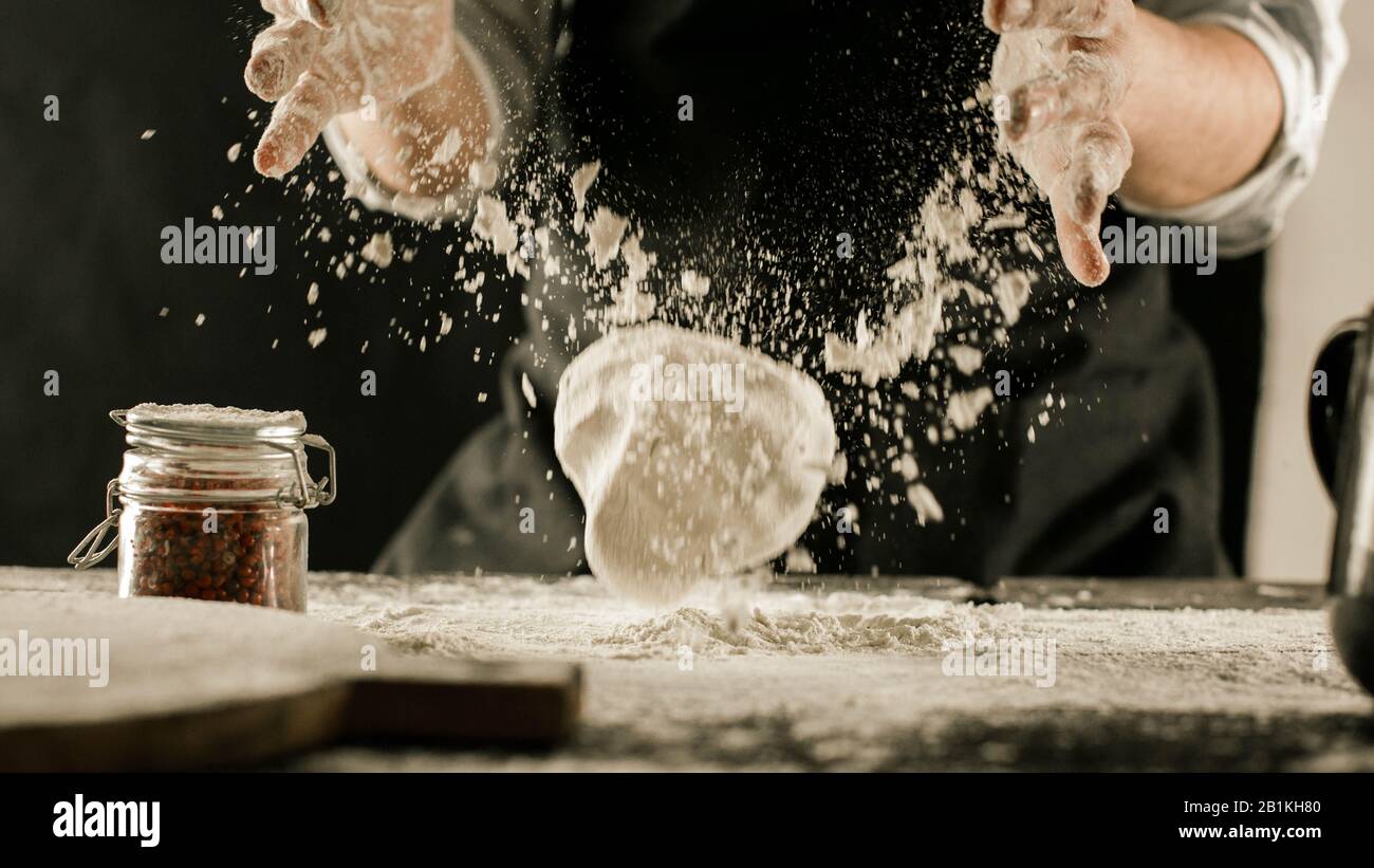 Male chef hands knead dough with flour on kitchen table side view Stock ...