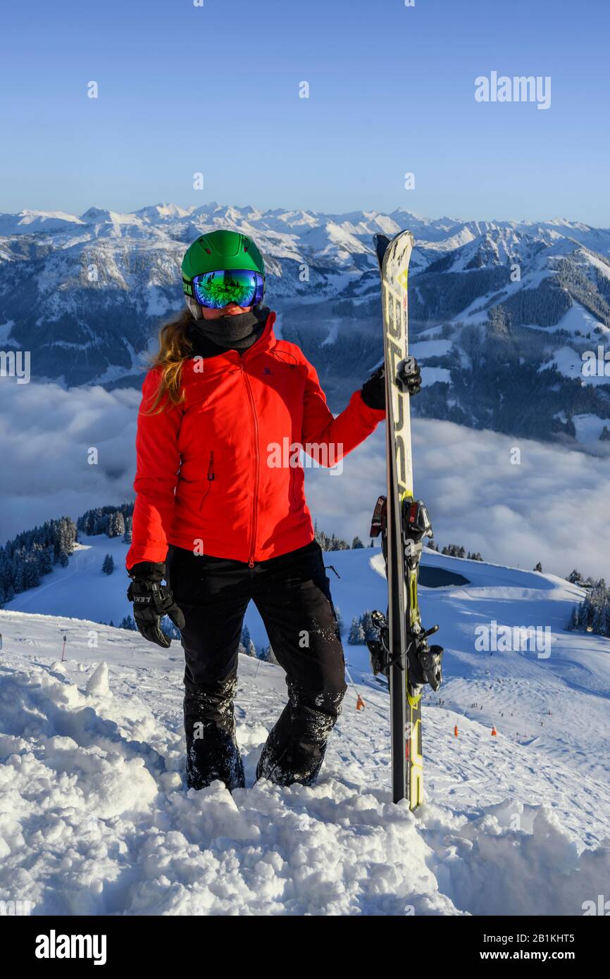 Skier with ski helmet and skis standing at the ski slope, looking into the camera, mountain panorama in the back, SkiWelt Wilder Kaiser, Brixen im Stock Photo