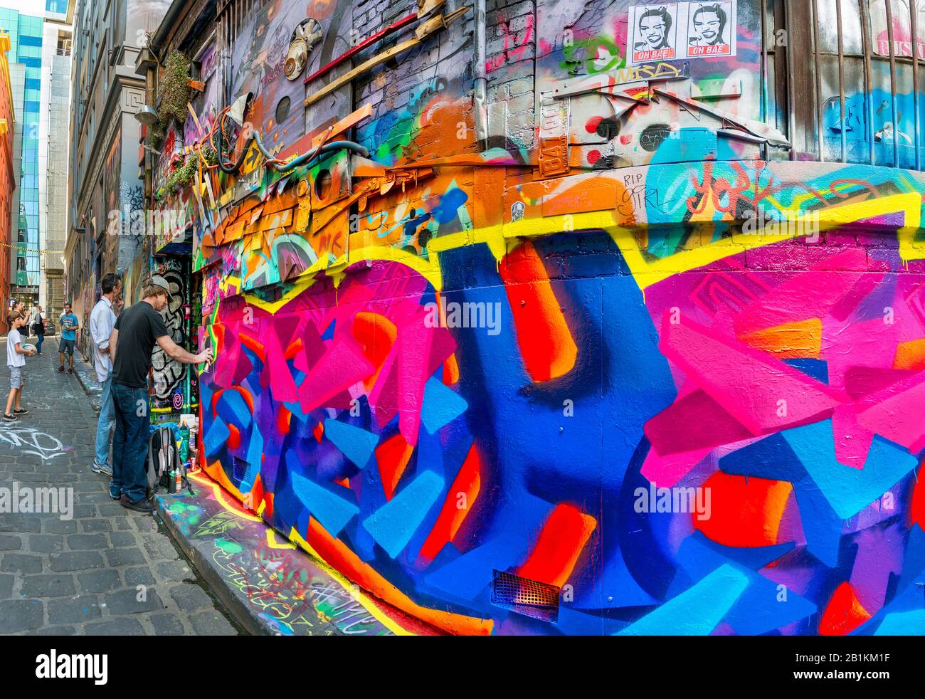 Young graffiti artist spray painting in cobbled stone alley way, Hosier Street, Melbourne Lanes, Melbourne, Victoria, Australia Stock Photo