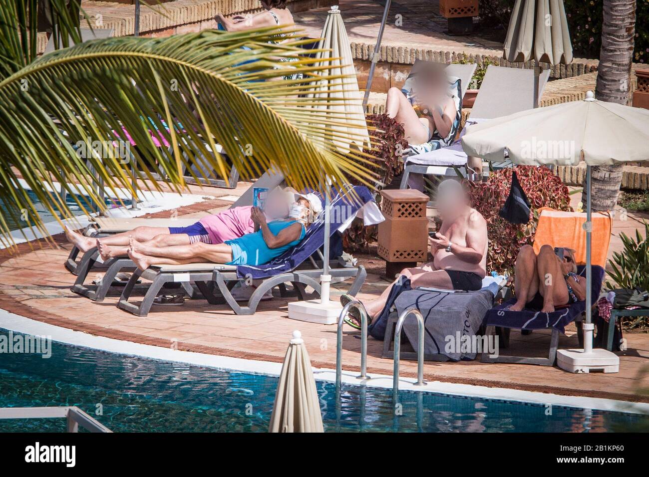 Teneriffa, Spain. 26th Feb, 2020. Hotel guests sunbathe by the pool. The hotel in Tenerife, which has been quarantined because of coronavirus cases, continues to be cordoned off by the police. Credit: Arturo Rodríguez/dpa - only for use in accordance with contractual agreement/dpa/Alamy Live News Stock Photo