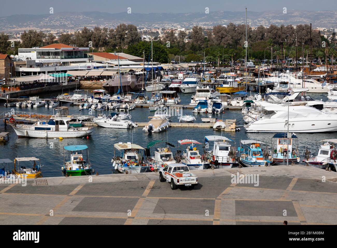 Traditional Cypriot fishing boats alongside  modern luxury yachts moored in Paphos harbour. Cyprus 2018. Stock Photo
