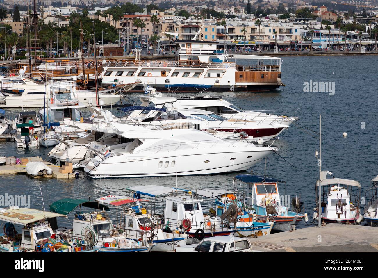Traditional Cypriot fishing boats alongside  modern luxury yachts moored in Paphos harbour. Cyprus 2018. Stock Photo