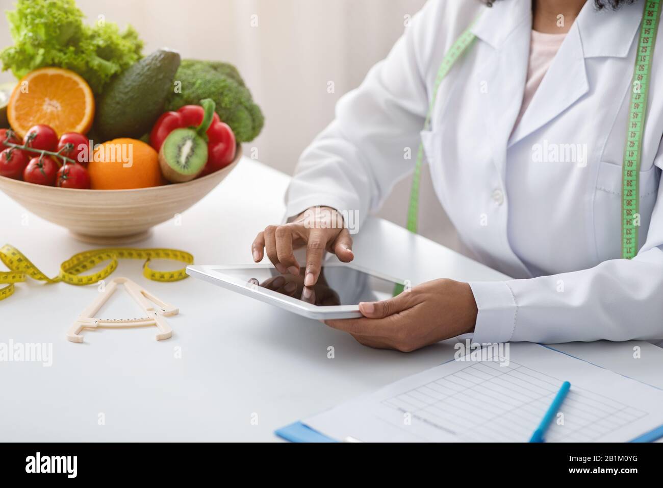 Dietologist black woman using digital tablet at workplace Stock Photo