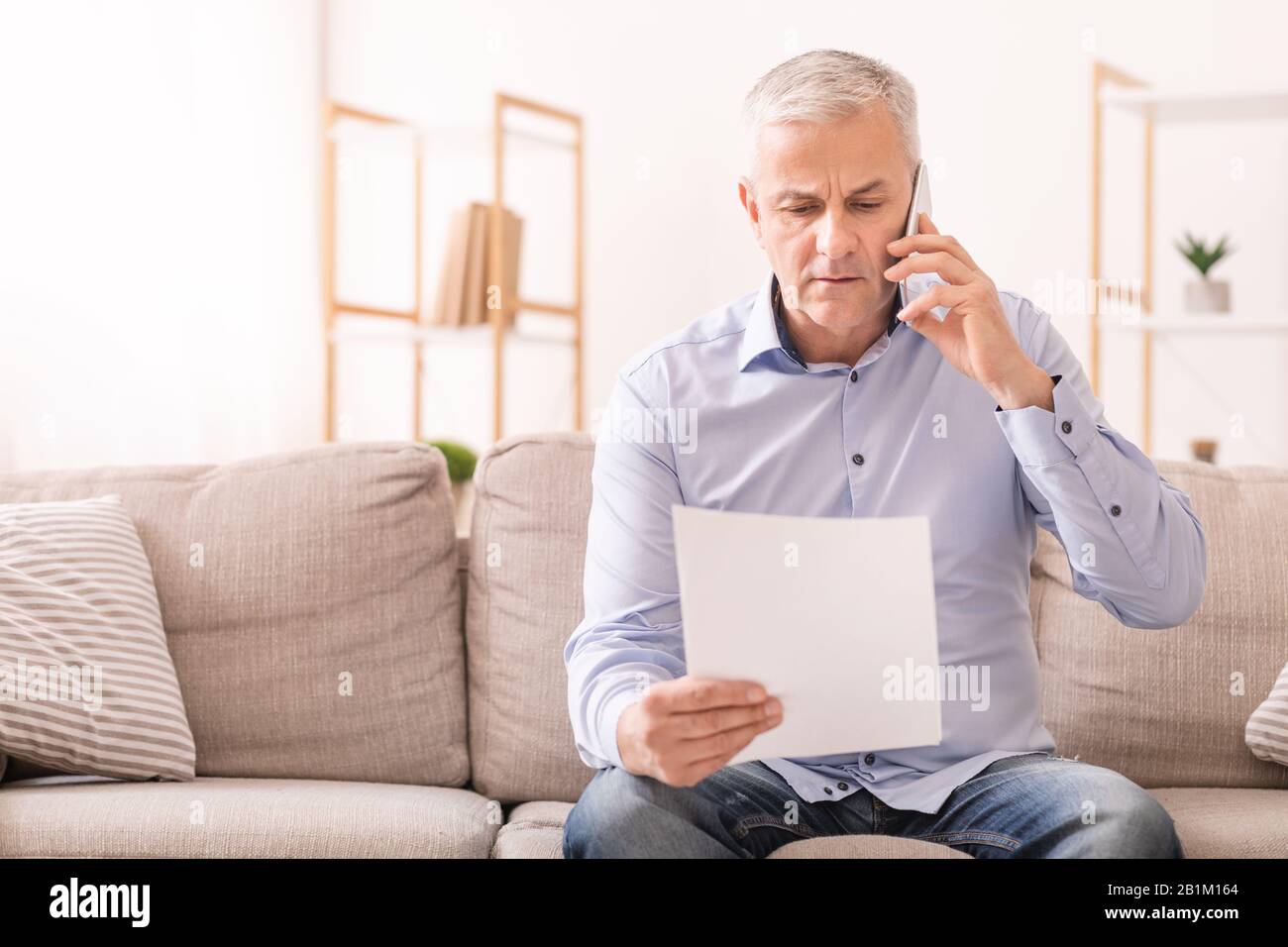 Senior man talking on mobile phone holding document Stock Photo