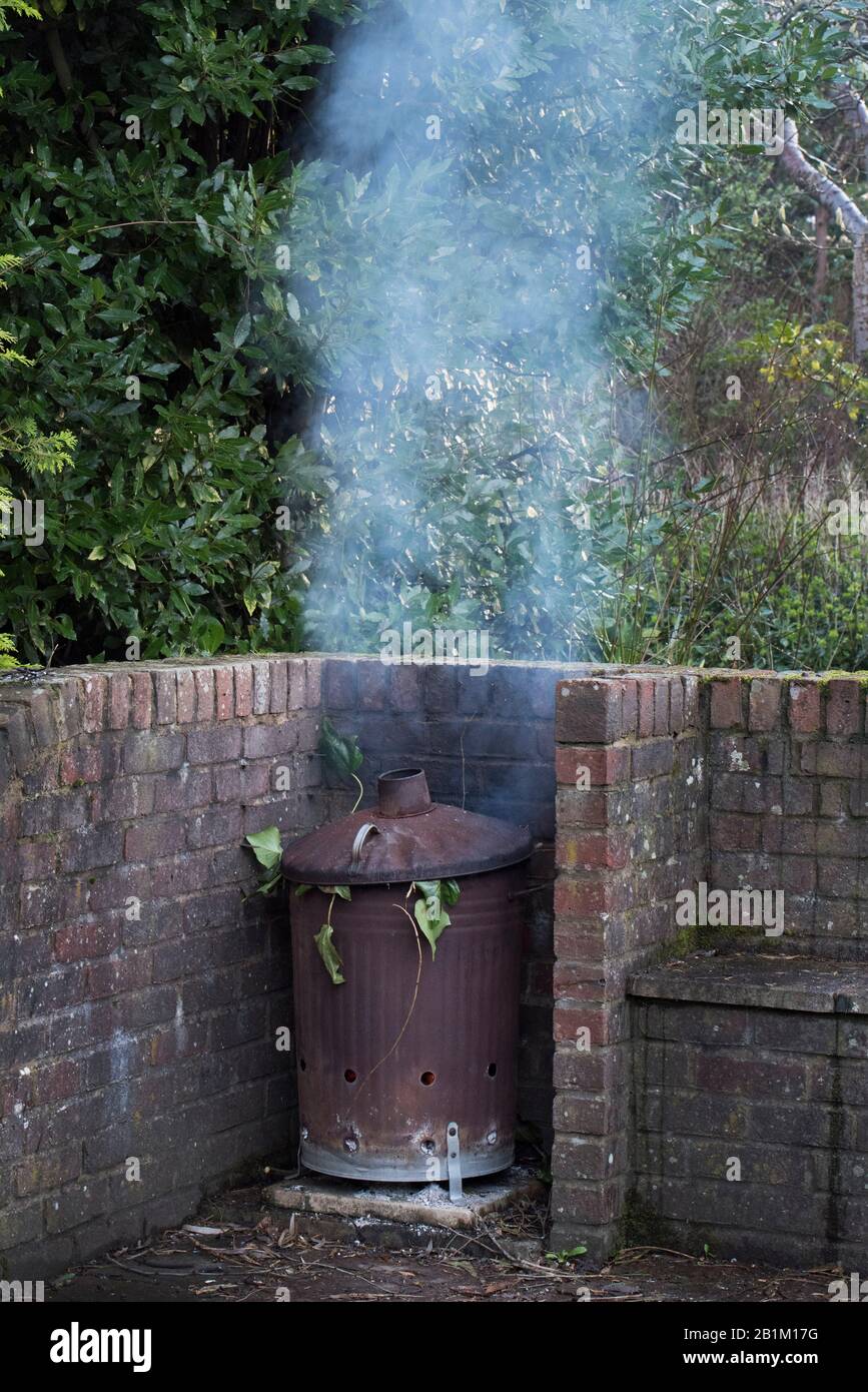 A Garden Incinerator Bin Rested on a Metal Chair Frame Burning