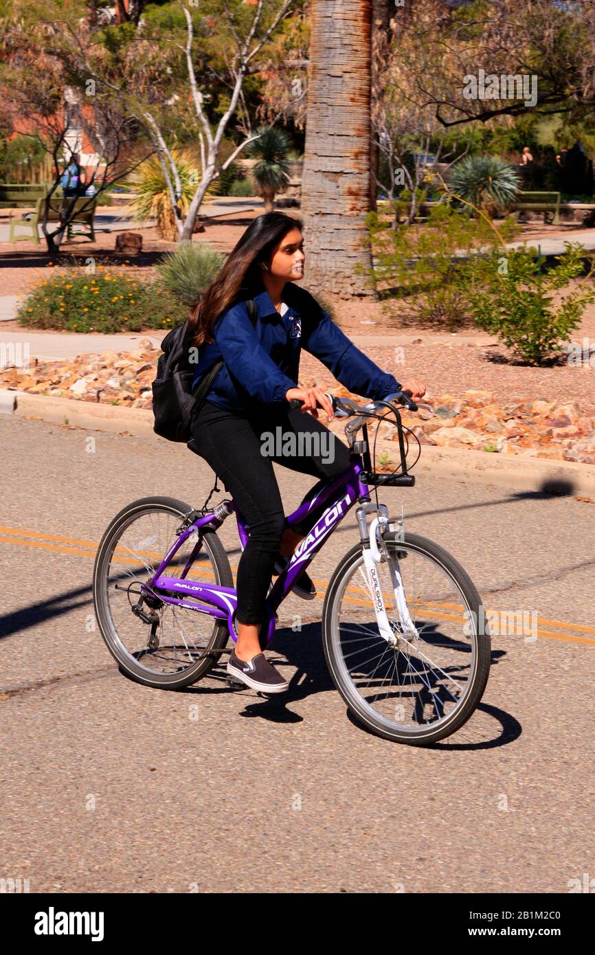 Beautiful hispanic female student on her bicycle riding thru the University of Arizona campus in Tucson Stock Photo