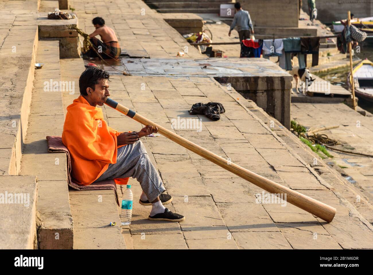 Man playing Didgeridoo on ganga river bank in morning. Varanasi. India