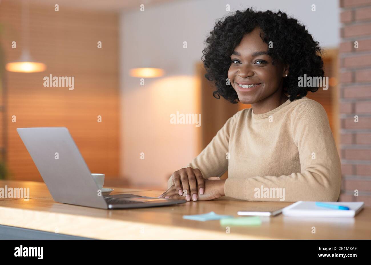 Positive black woman sitting at cafe. working online on laptop Stock Photo