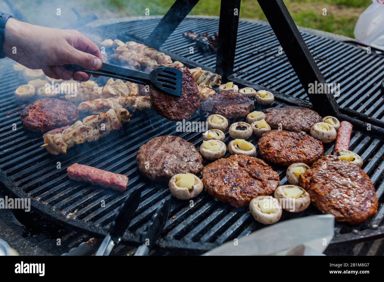 Preparing grilled meat on barbecue at picnic. Outdoor BBQ party Stock Photo  - Alamy