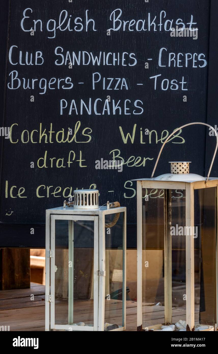 a chalkboard menu and information sign at a cafe in greece advertising pancakes and full english breakfasts, toasts and sandwiches. Stock Photo