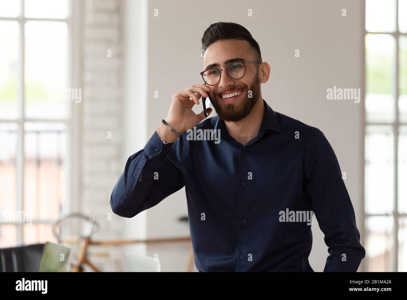 Millennial middle eastern ethnicity businessman talking on phone in office Stock Photo