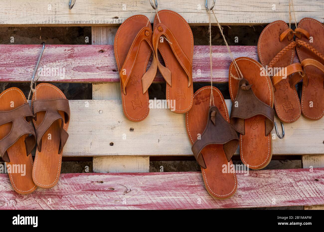 Flip-flops or sandals hanging from a wooden fence to dry in the summer sunshine. Stock Photo