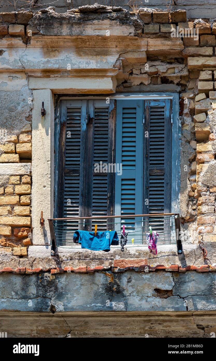 an old shabby chic style window with wooden shutters on a tumbledown greek building on the island of corfu in greece. Stock Photo