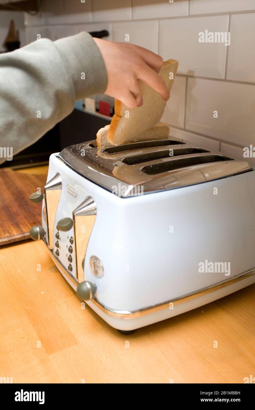 young girl putting bread into toaster Stock Photo Alamy