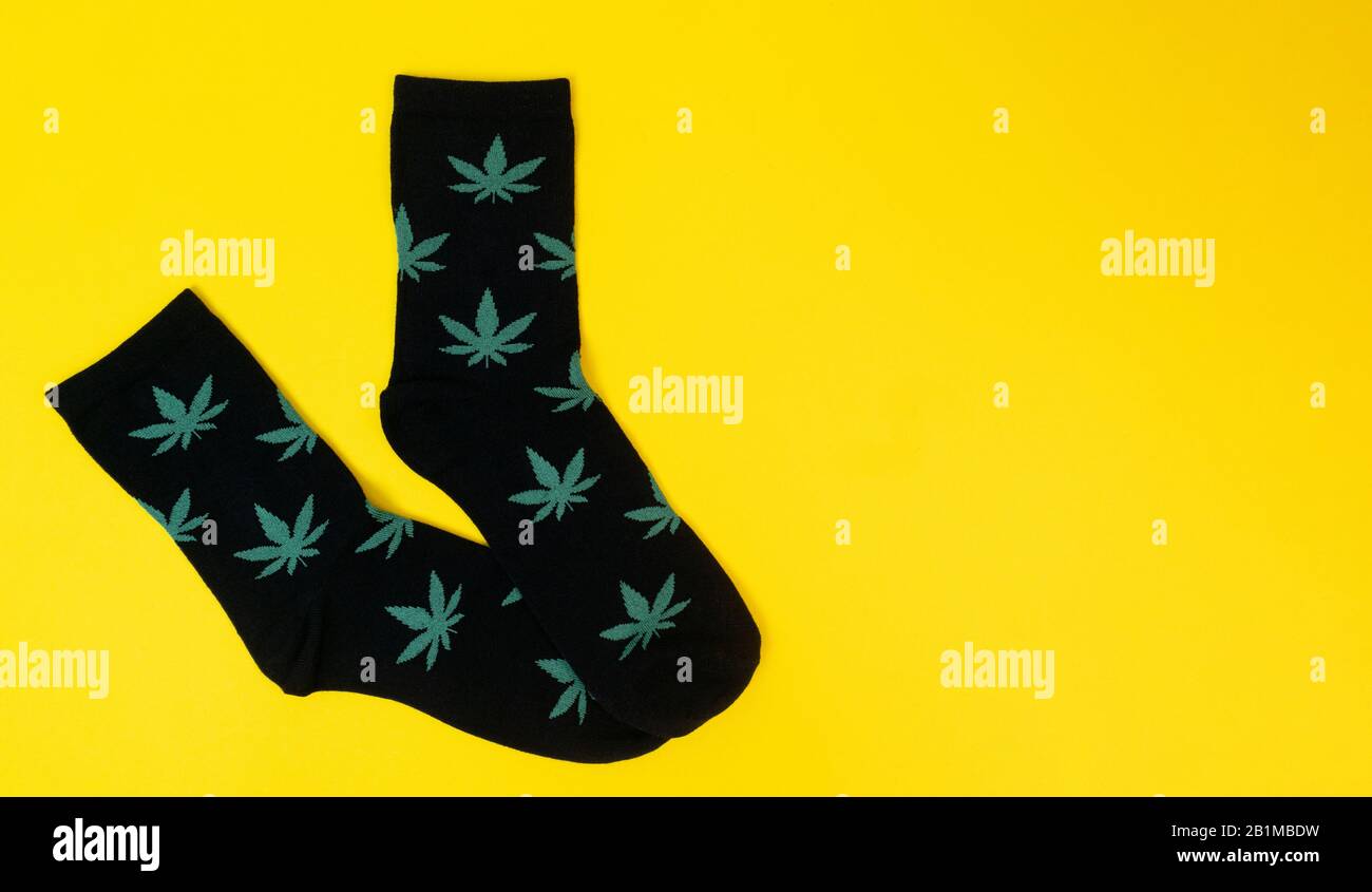 socks with cannabis leaves on yellow background Stock Photo