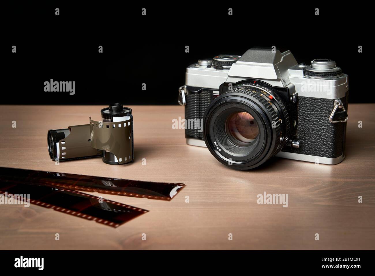 front view of a Classic analog 35 mm camera vintage and analog film rolls on wooden table Stock Photo