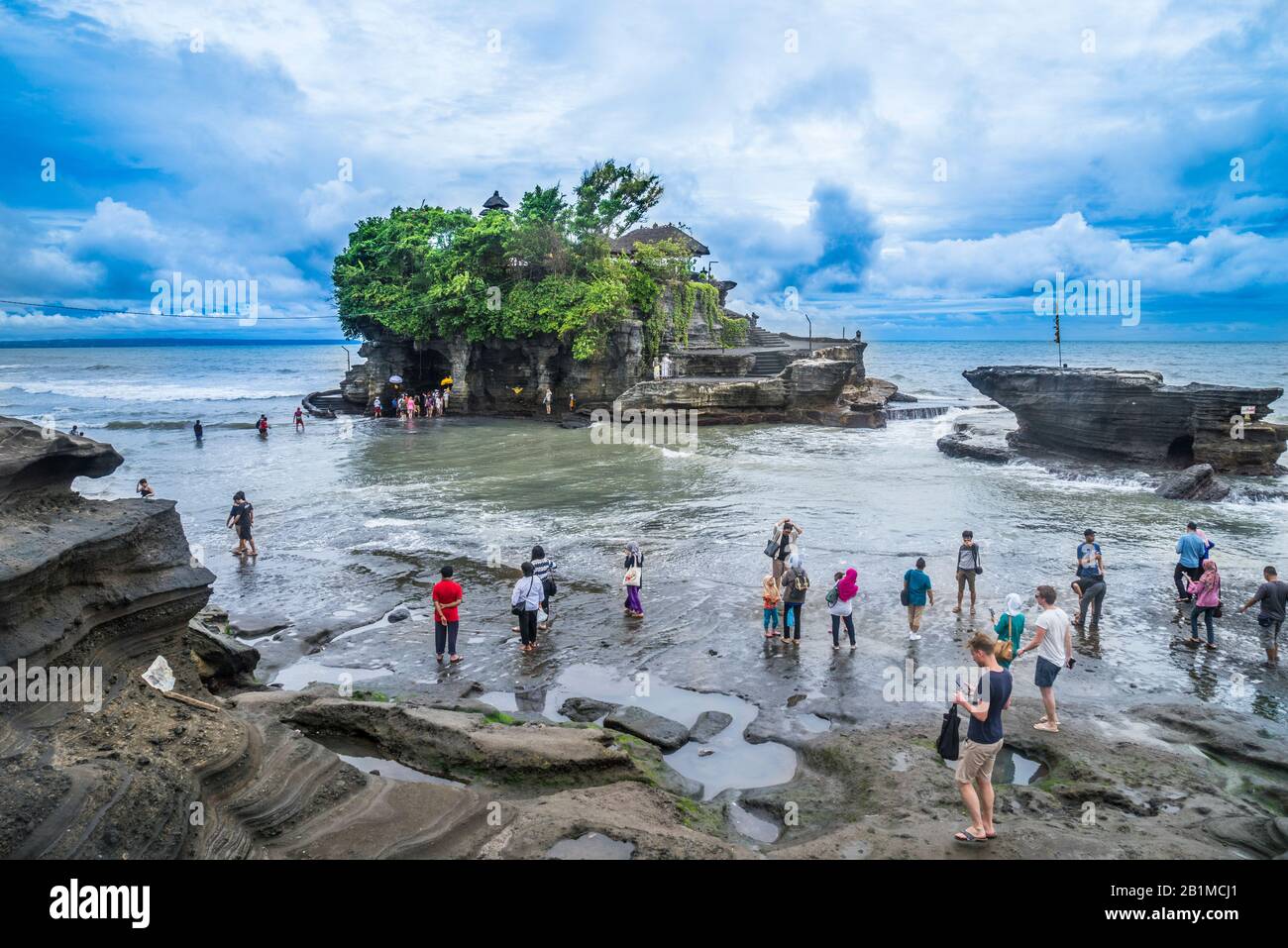 visitors and pilgrims at Tanah Lot, a rock formation off the Indonesian island of Bali, home to an ancient Hindu pilgrimage temple Pura Tanah Lot, Bal Stock Photo