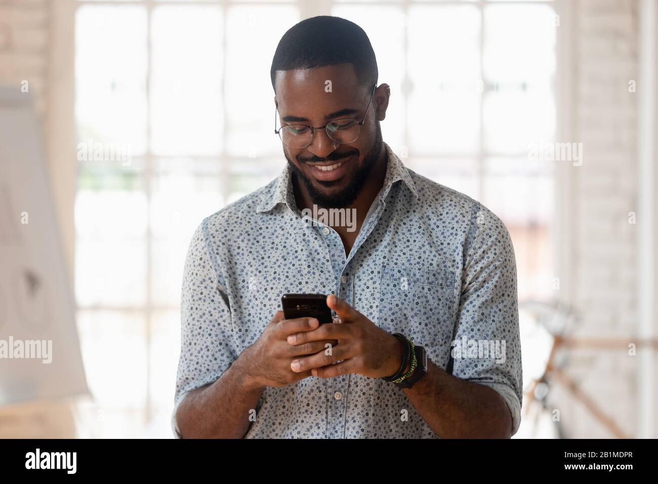 African guy holds phone using apps take break during workday Stock Photo