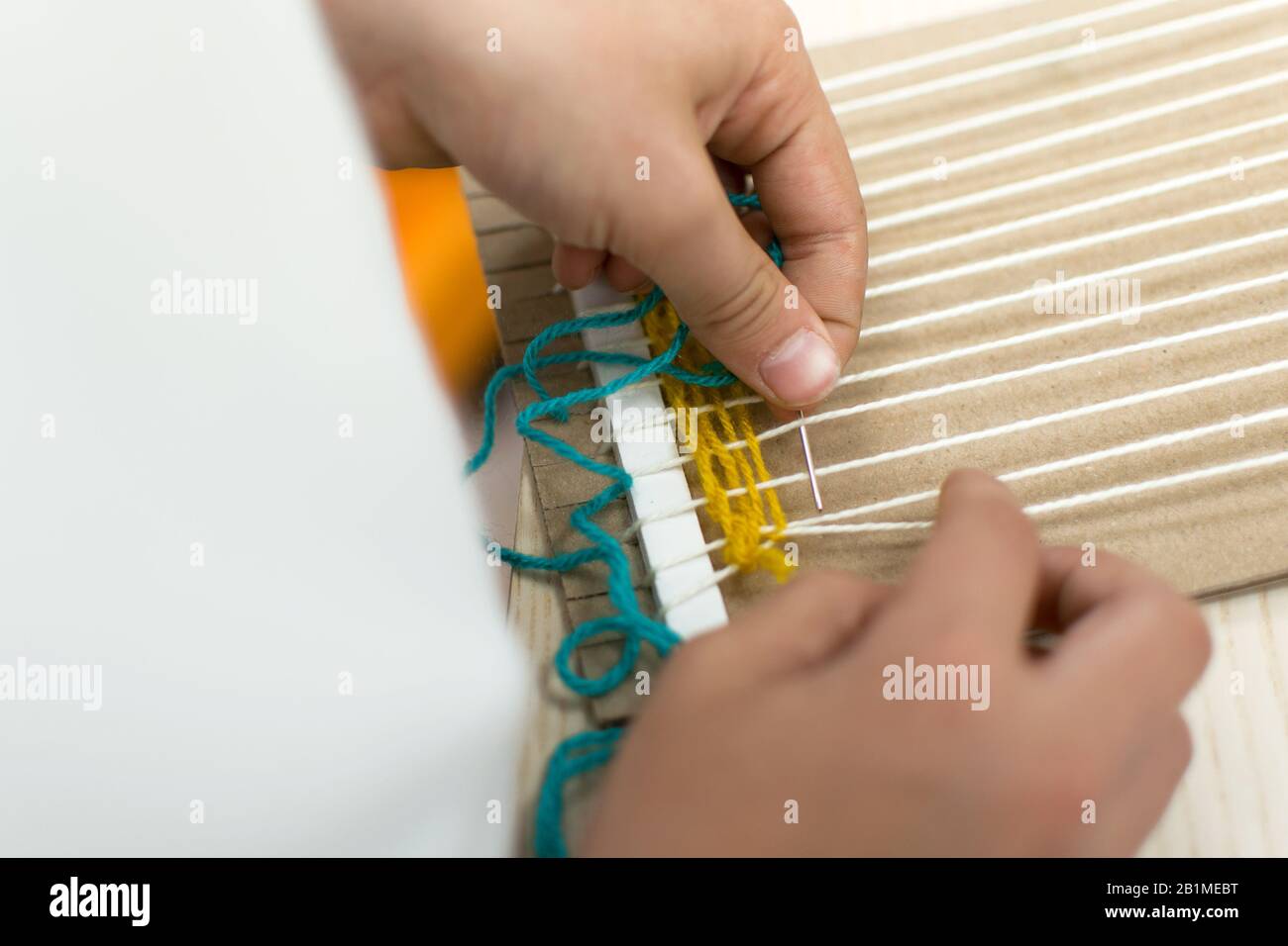 Little children hands weaving loom in art theraphy class at school. Education concept. Telar