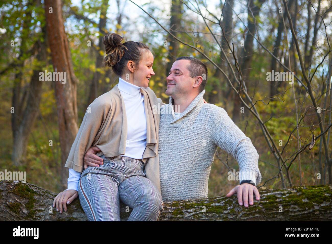 Beautiful couple sitting together on the tree in park hugging Stock ...