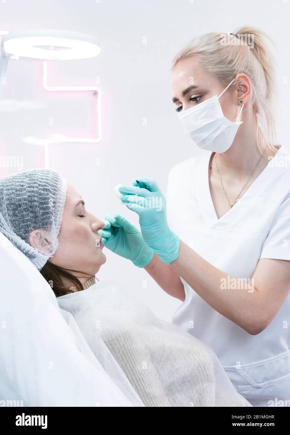 The young beautician doctor preparing to making injection in female forehead. The doctor cosmetologist makes anti-aging treatment and face lift proced Stock Photo