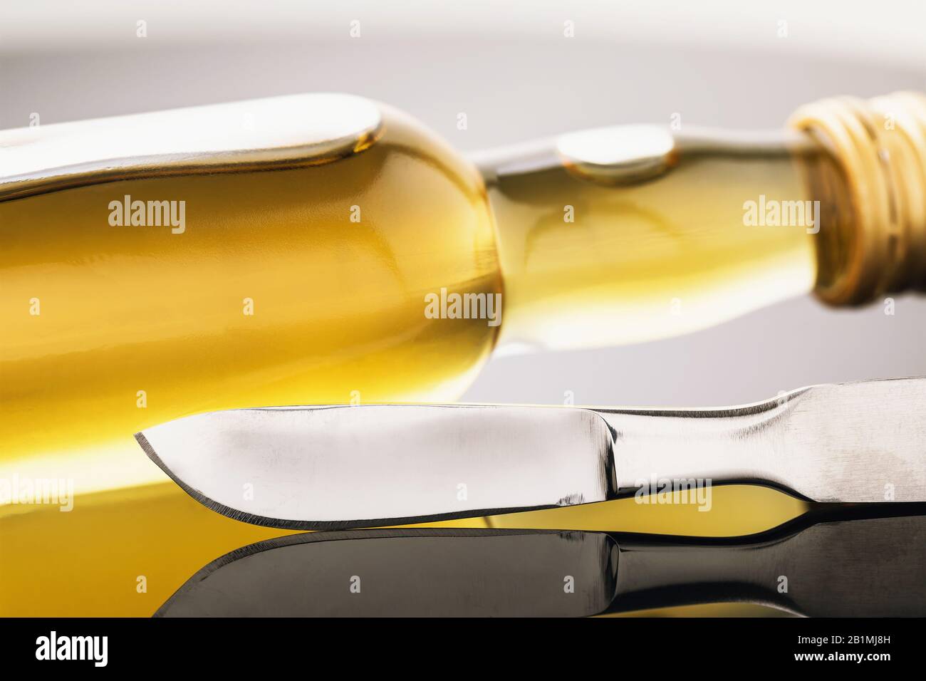 Scalpel and a bottle of whiskey on the table, closeup. Concept of alcohol abuse by doctors Stock Photo