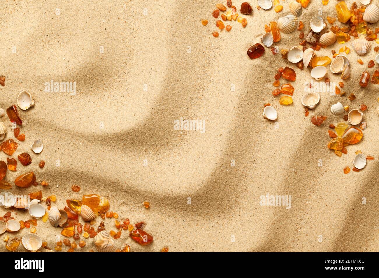 Ambers and seashells on sand background. Flat lay. Top view Stock Photo
