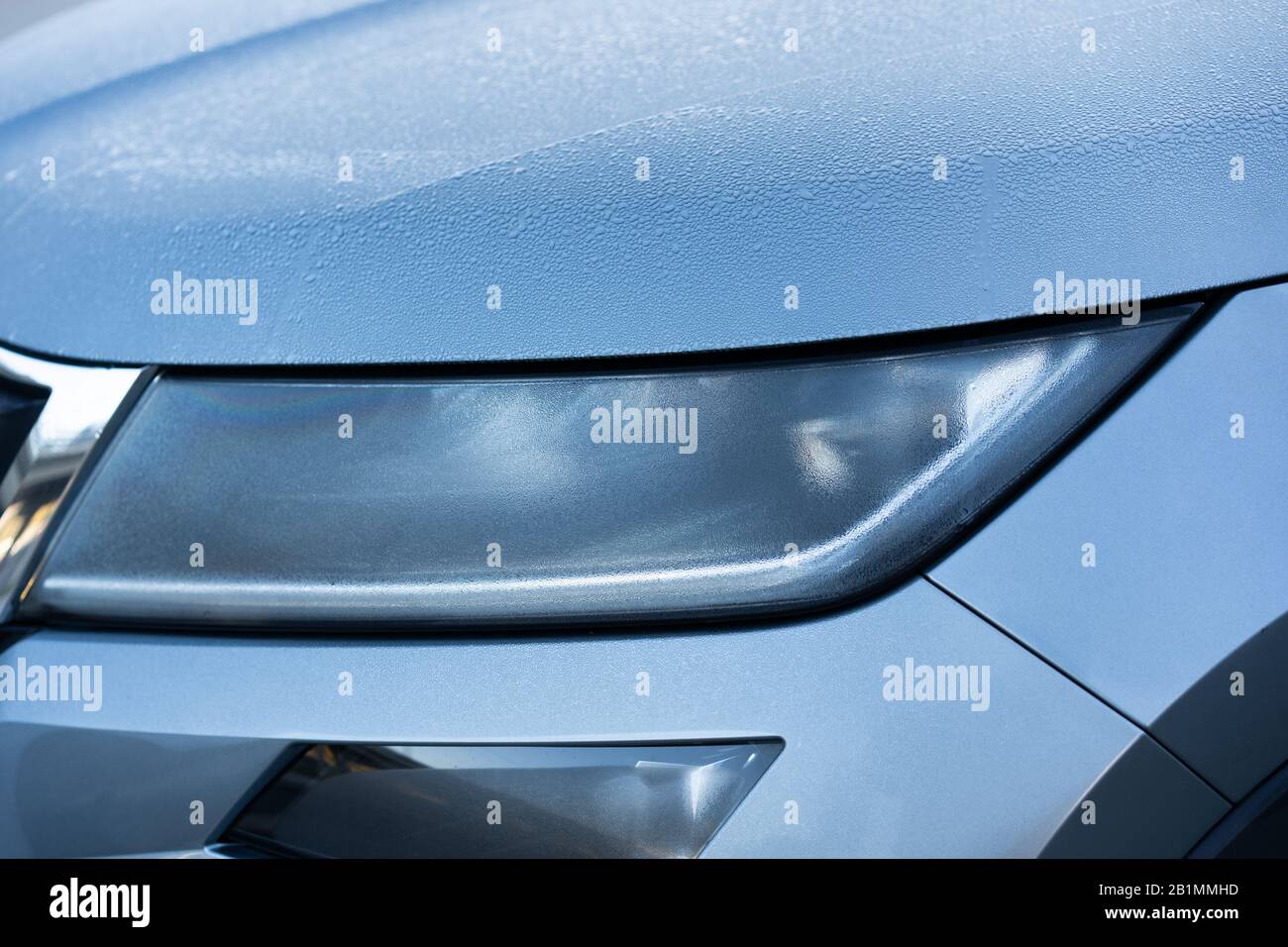 Headlight detail of blue car with water drop after car wash. Close up