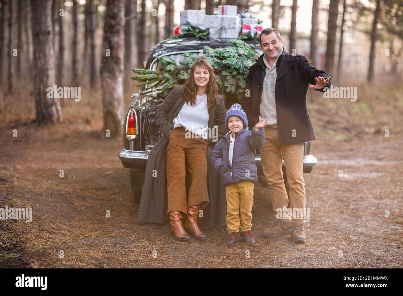 Smiling Adult Man And Woman With Boy In Warm Clothes Standing At Vintage Car With Christmas Presents Stock Photo Alamy
