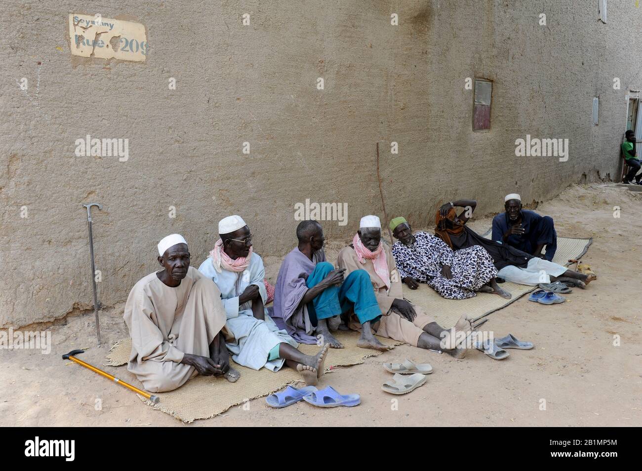 MALI, Djenne, muslim men sitting infront of clay building Stock Photo