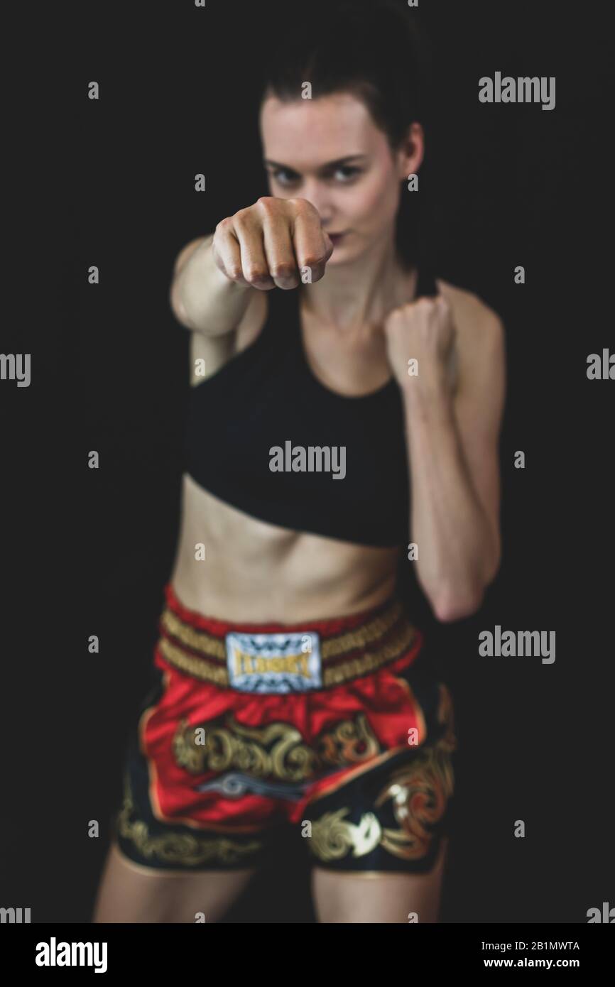 Model wearing boxing outfit smiling while throwing a punch at camera. Royalty free stock photo. Stock Photo
