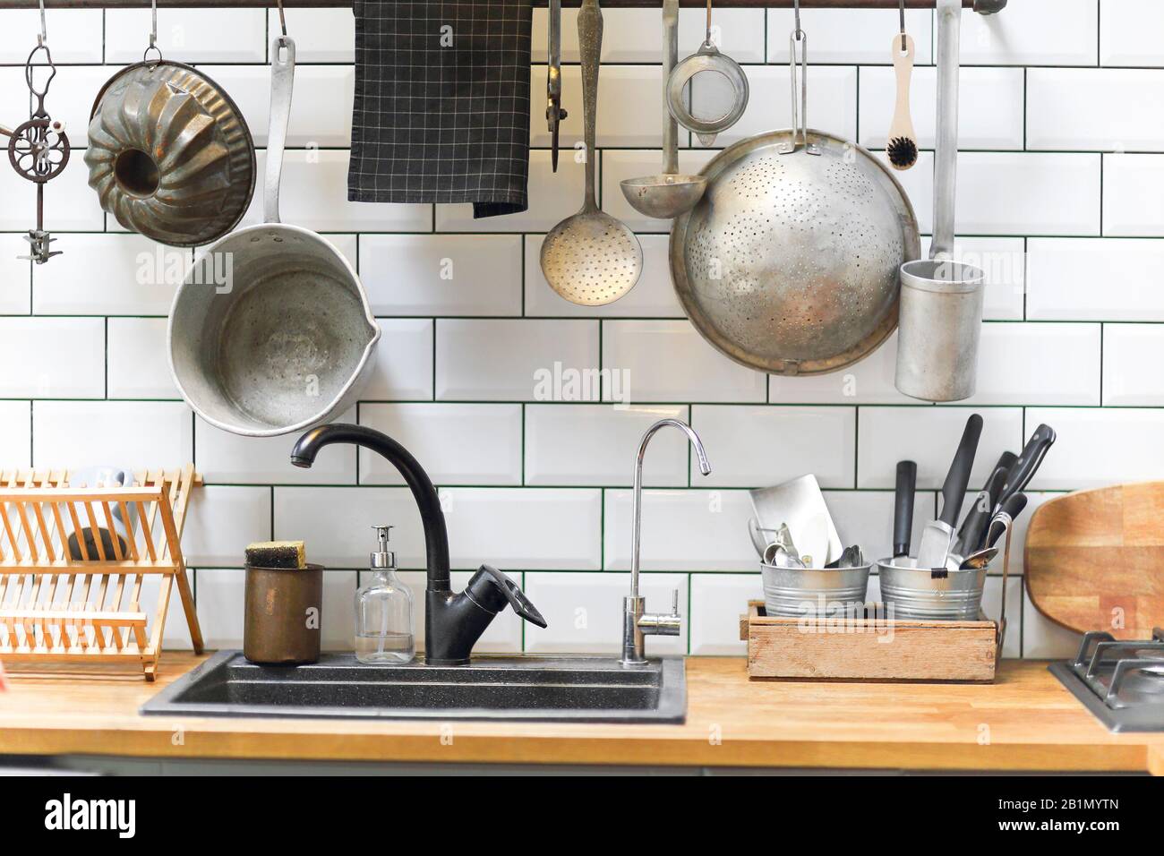 Various vintage kitchenware arranged on wall and counters near sink in